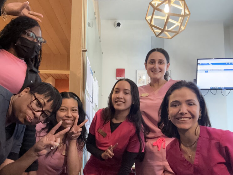 Walk In GYN Care staff members in pink scrubs posing together inside a New York City women’s healthcare clinic.